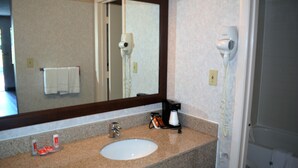 A bathroom with a sink, a mirror, a hairdryer, and a towel rack.