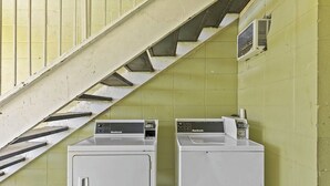 Two white front-loading washing machines against a yellow wall with a staircase. - Star Motel Hattiesburg University Area (Hattiesburg)