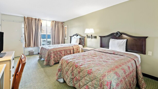 A hotel room with two beds, a desk, a chair, a lamp, and a window with curtains. - Star Motel Hattiesburg University Area (Hattiesburg)