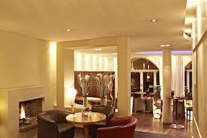 A spacious lounge area with a fireplace, leather seating, and a well-lit interior.