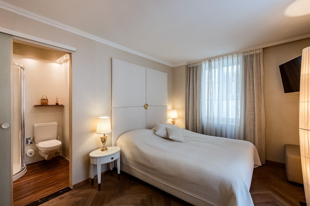Une chambre d’hôtel avec un grand lit, des lampes de chevet, une télévision et une vue sur l’extérieur par une fenêtre.