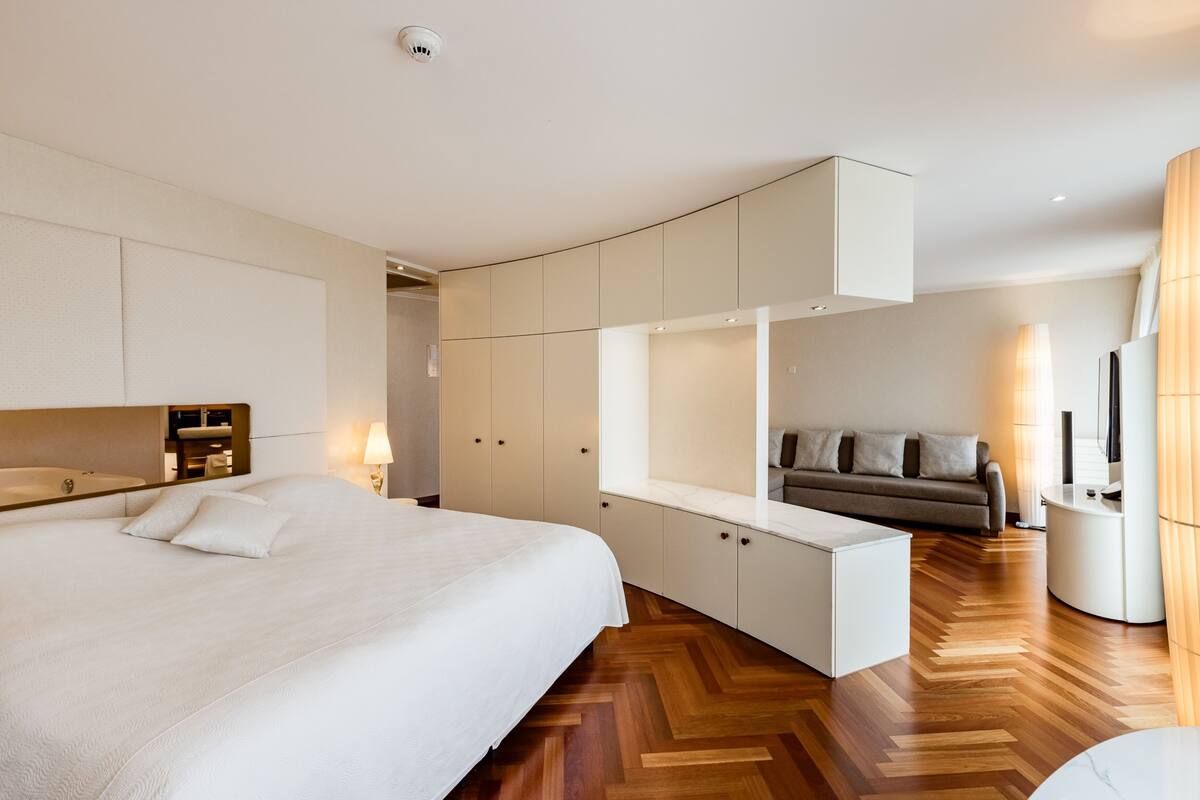 Une chambre d’hôtel moderne dotée d’un grand lit, d’une armoire intégrée, d’un coin salon et d’un canapé.