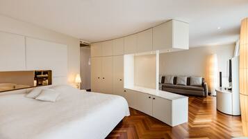 Una habitación de hotel moderna con una cama grande, armario empotrado, zona de estar y sofá.