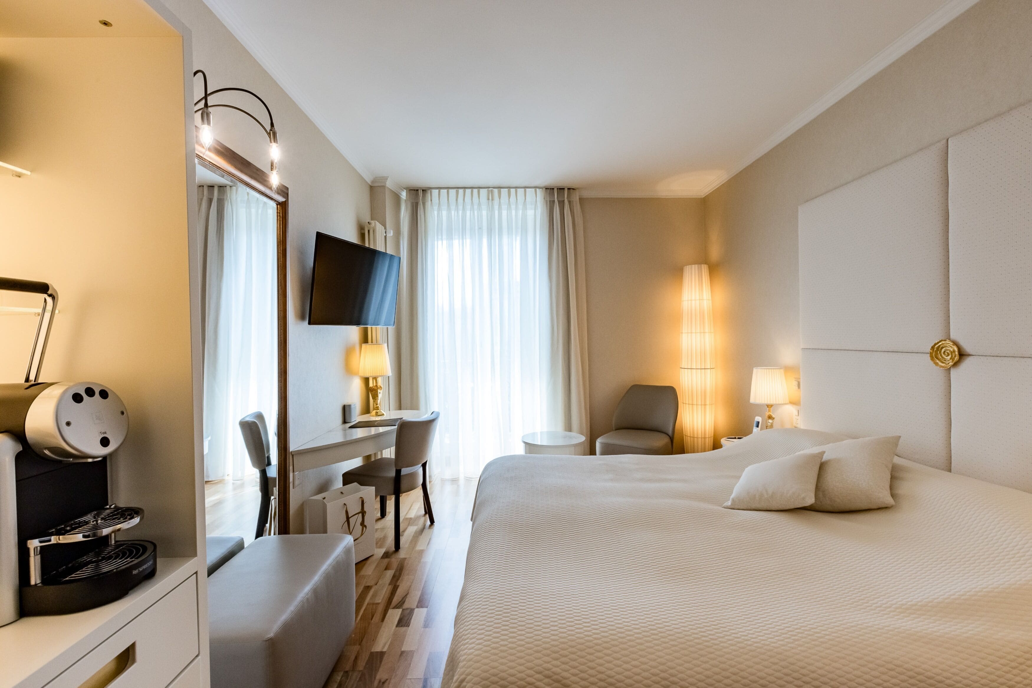 Ein Hotelzimmer mit Bett, Schreibtisch, Stuhl, Fernseher und einer Kaffeemaschine.