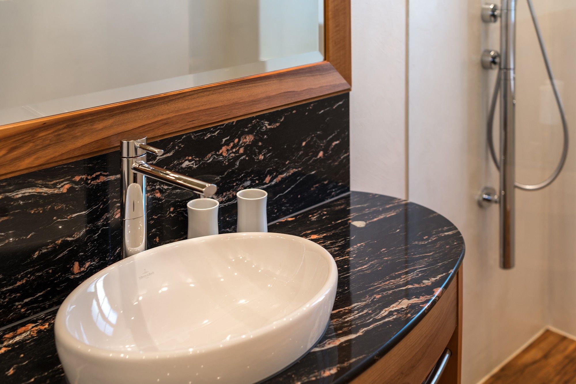 A bathroom with a white sink, a mirror, and a shower.