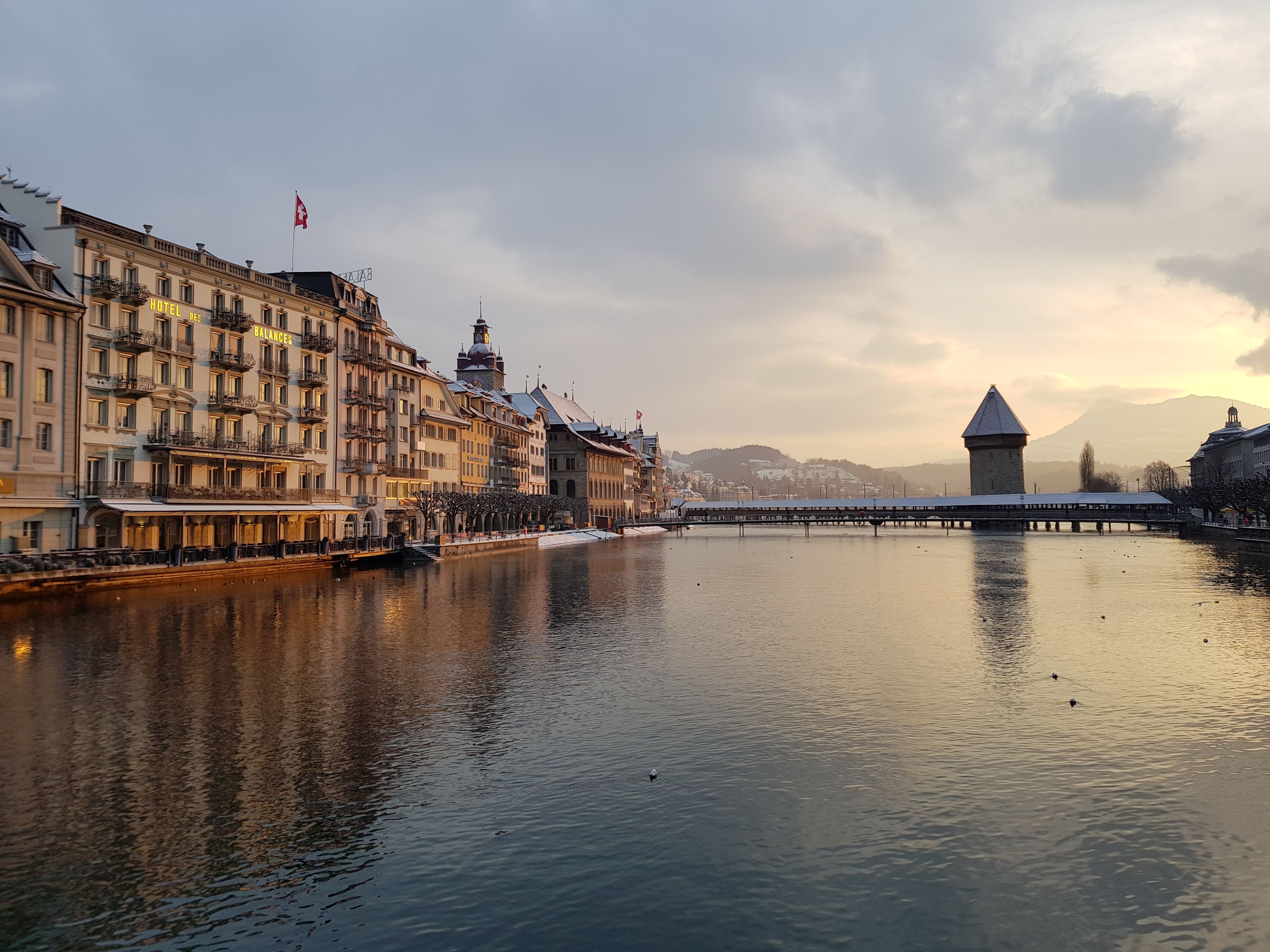 A riverside view of a hotel with a bridge and a tower in the background.