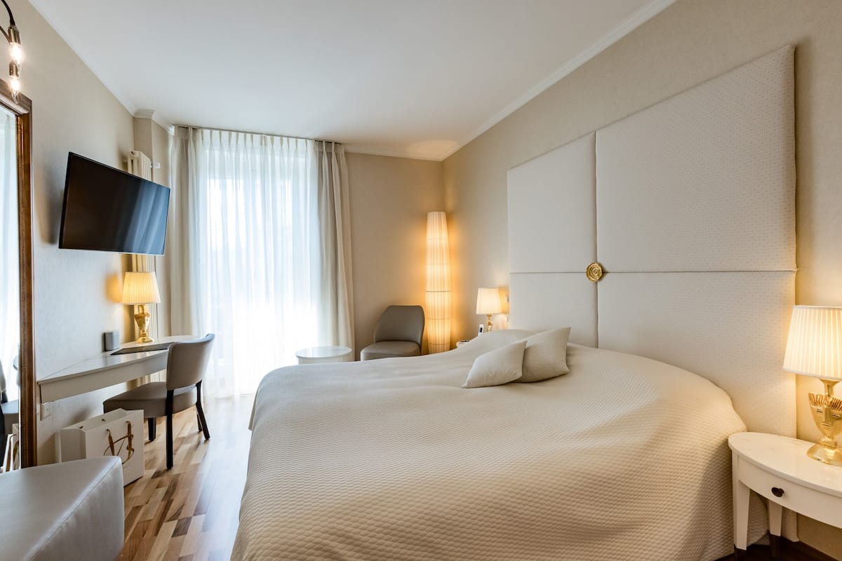 Une chambre d’hôtel avec un grand lit, un bureau avec une chaise, une télévision et deux lampes.