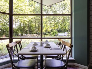 A dining area with a table set for four, large windows, and a view of the outdoors.