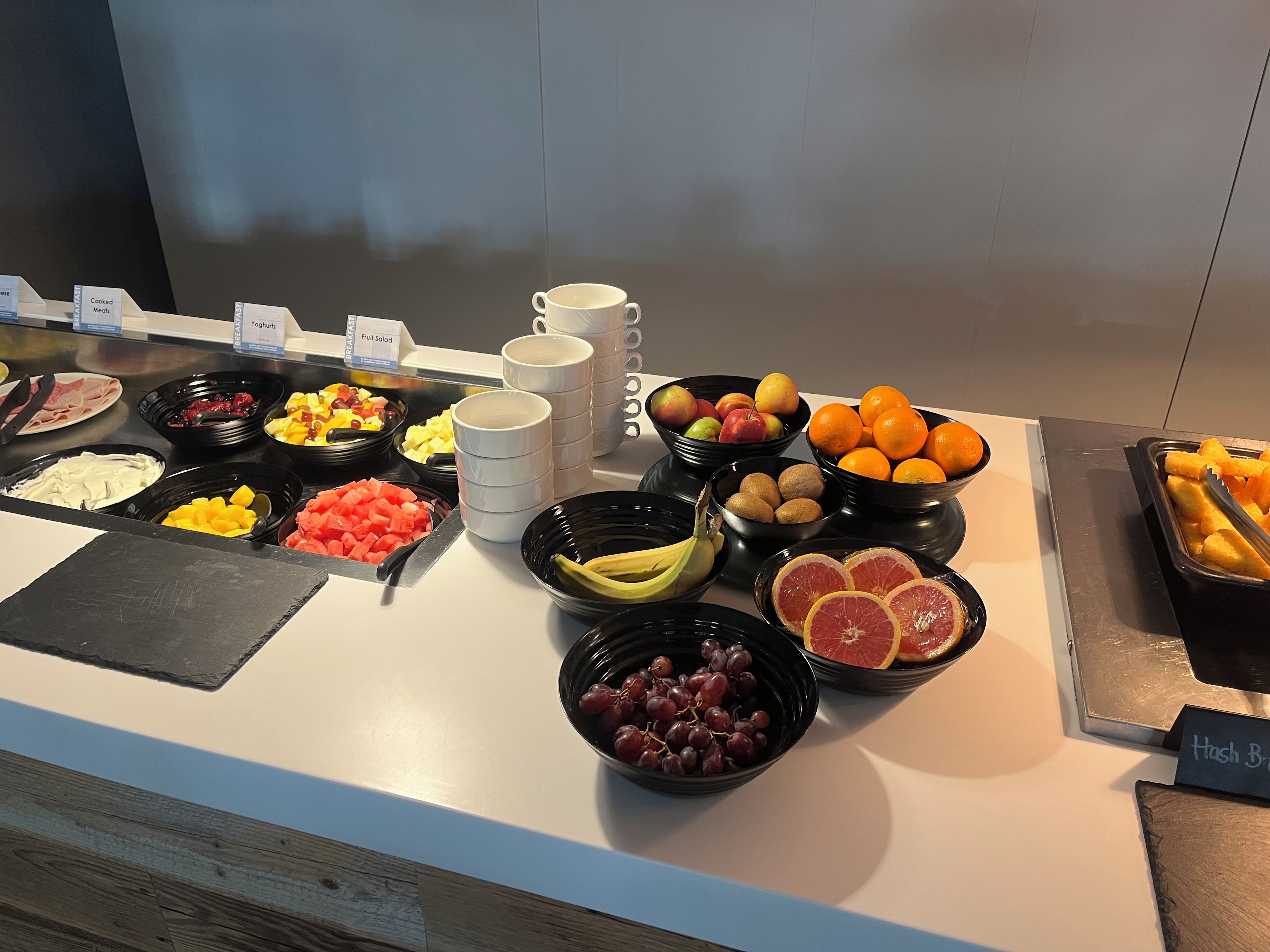 A buffet with various food items including fruits, yogurts, and cooked meats.