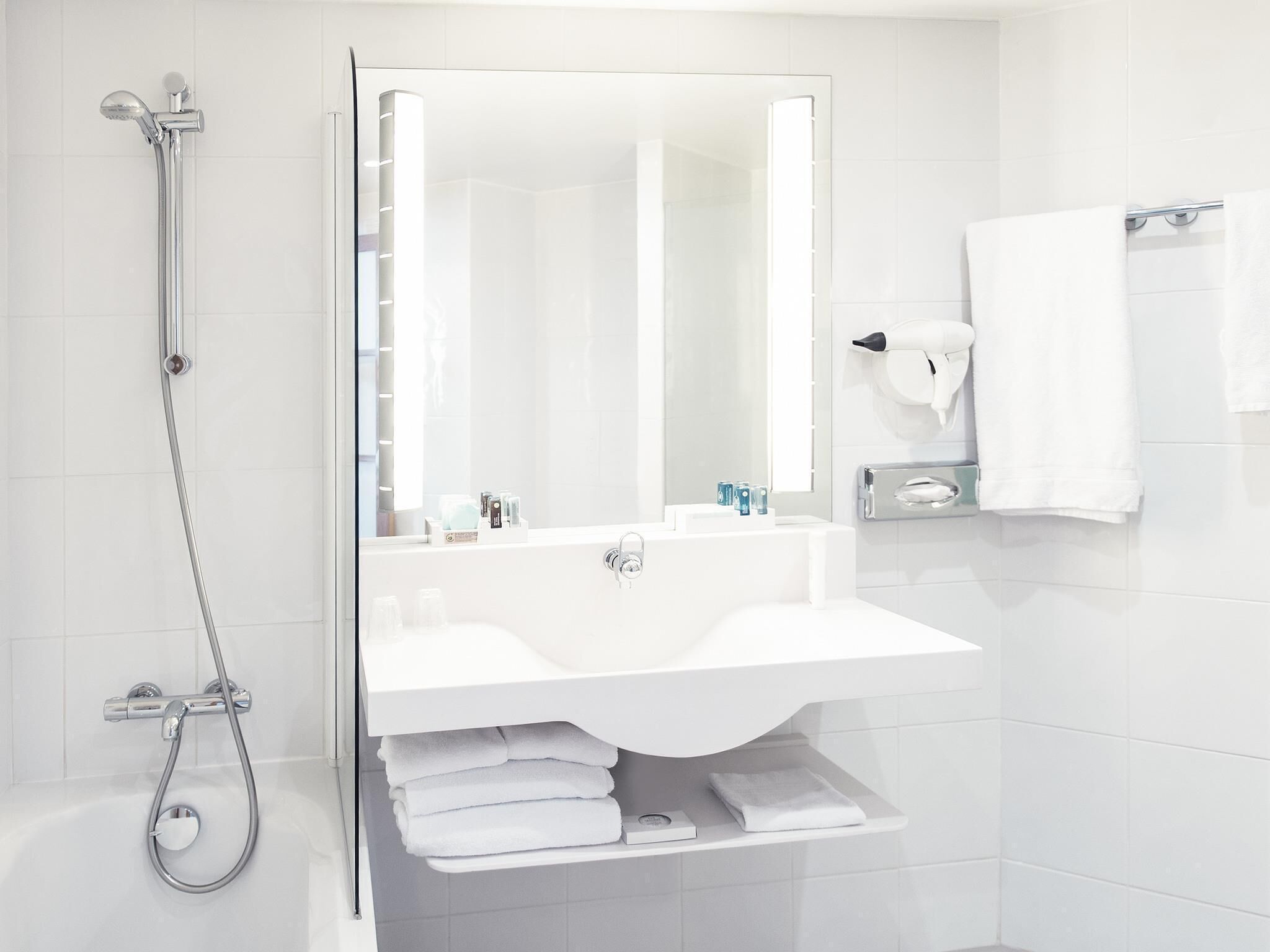 Une salle de bain moderne avec une douche, un lavabo et un miroir.