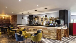 A modern bar area with wooden furniture, a checkered floor, and a brick wall.