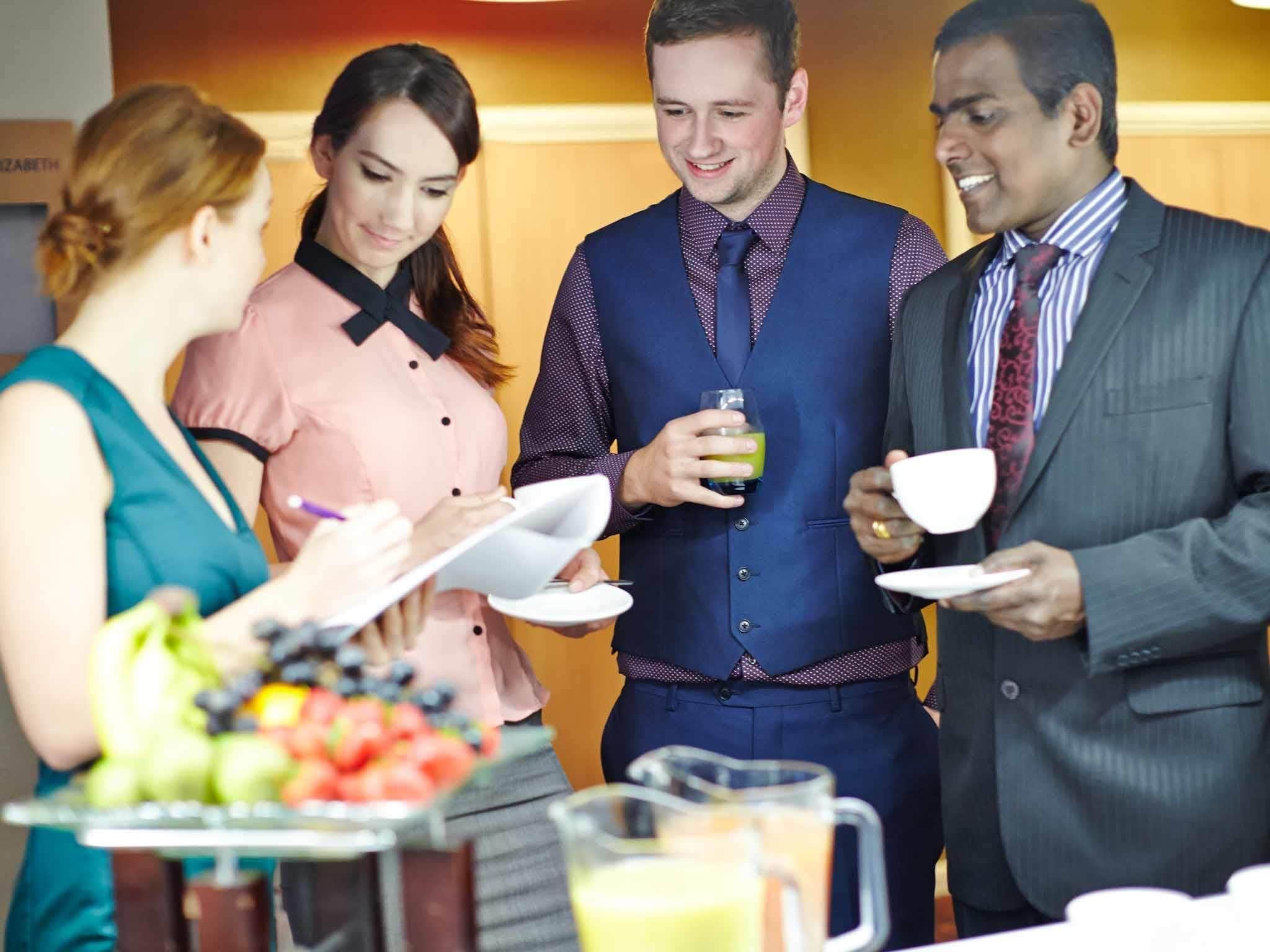 A group of people at a buffet with a variety of fruits and a pitcher of juice.
