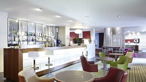 Eine moderne Bar mit einer Auswahl an Spirituosenflaschen, einer Theke und Sitzgelegenheiten mit runden Tischen und Stühlen.