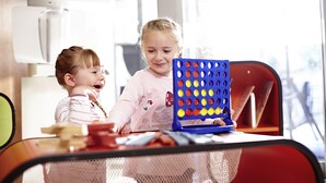 Zwei Kinder spielen an einem Tisch mit einem Puzzlespiel.