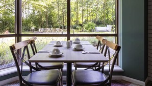A dining area with a table set for four, large windows, and a view of the outdoors.