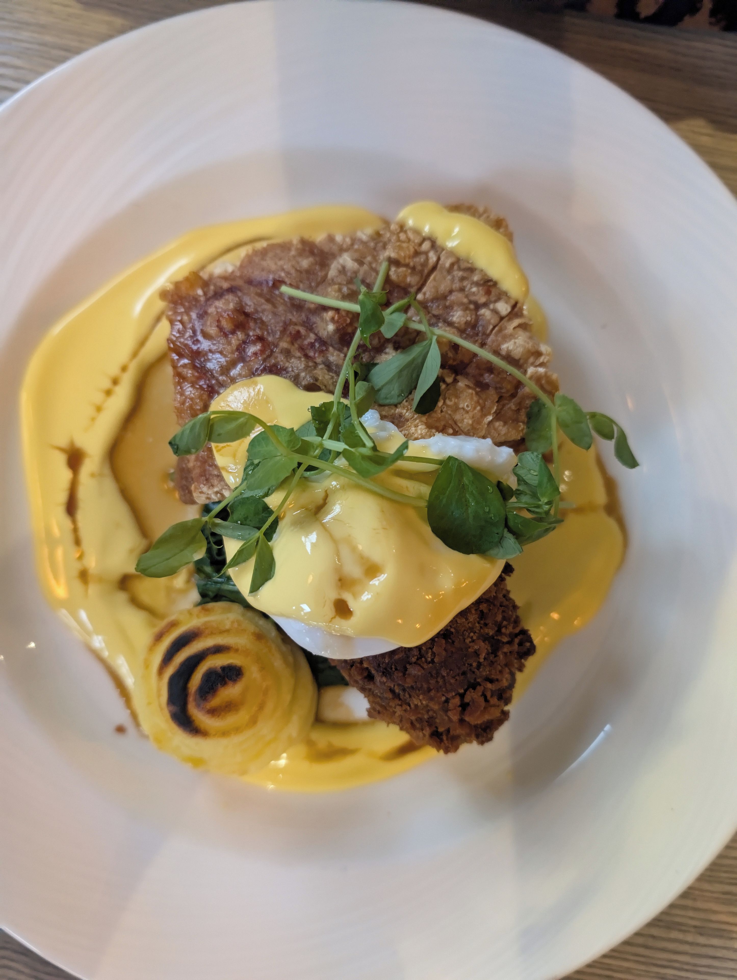 A plate with a food item, possibly a steak, topped with a creamy sauce and garnished with greens.
