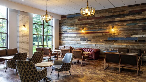 A modern interior with a herringbone wooden floor, leather seating, and a brick accent wall.