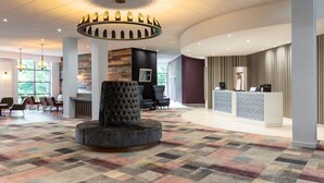 A hotel lobby with a central seating area, a reception desk, and a patterned carpet.