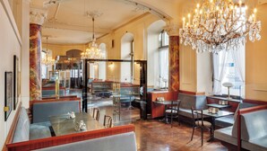 Un'ampia hall dell'hotel con lampadari decorati, zone relax e una maestosa scalinata.