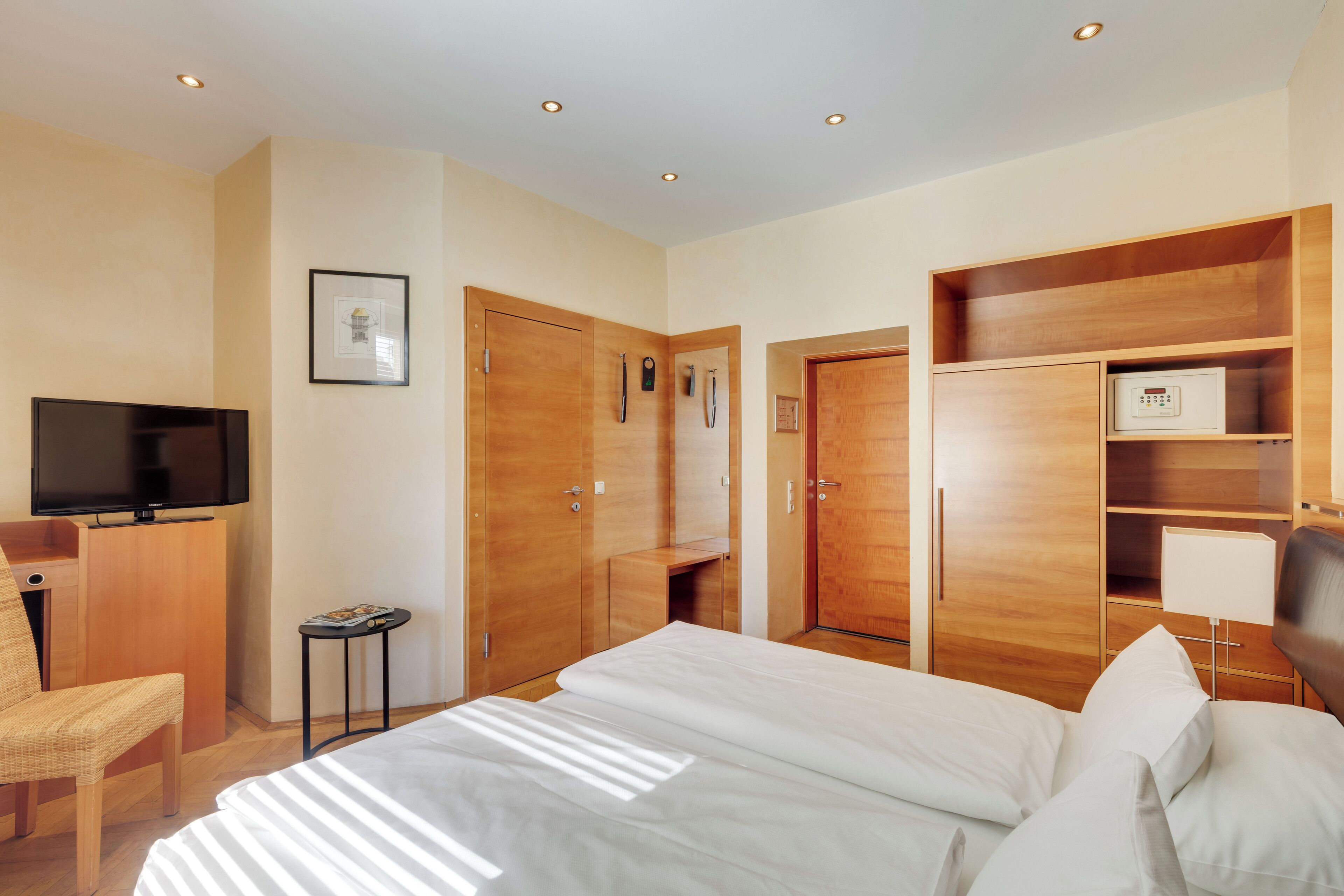 Een hotelkamer met een bed, een televisie, houten kasten, een klein tafeltje en een stoel.