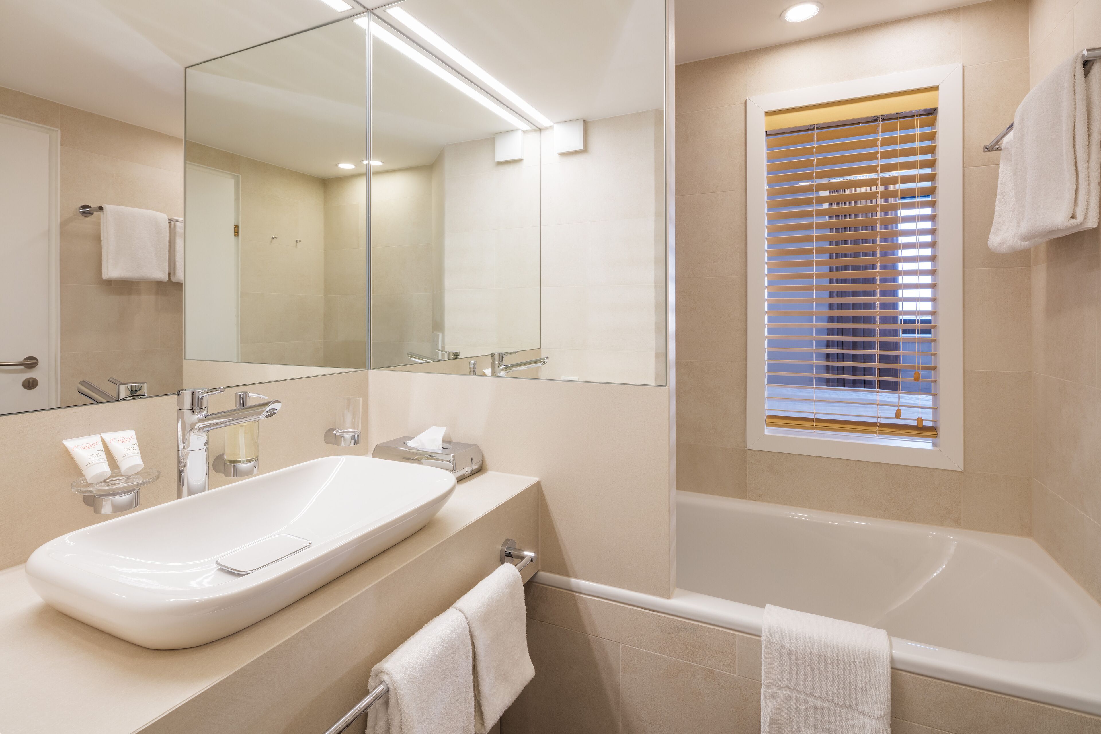 A modern bathroom with a large sink, mirror, and bathtub.