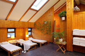 A wooden room with two beds, a small table, and a potted plant. - Hotel Central (Innsbruck)
