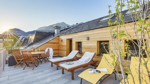 Una baita in legno con una terrazza, poltrone da relax e un tavolo.