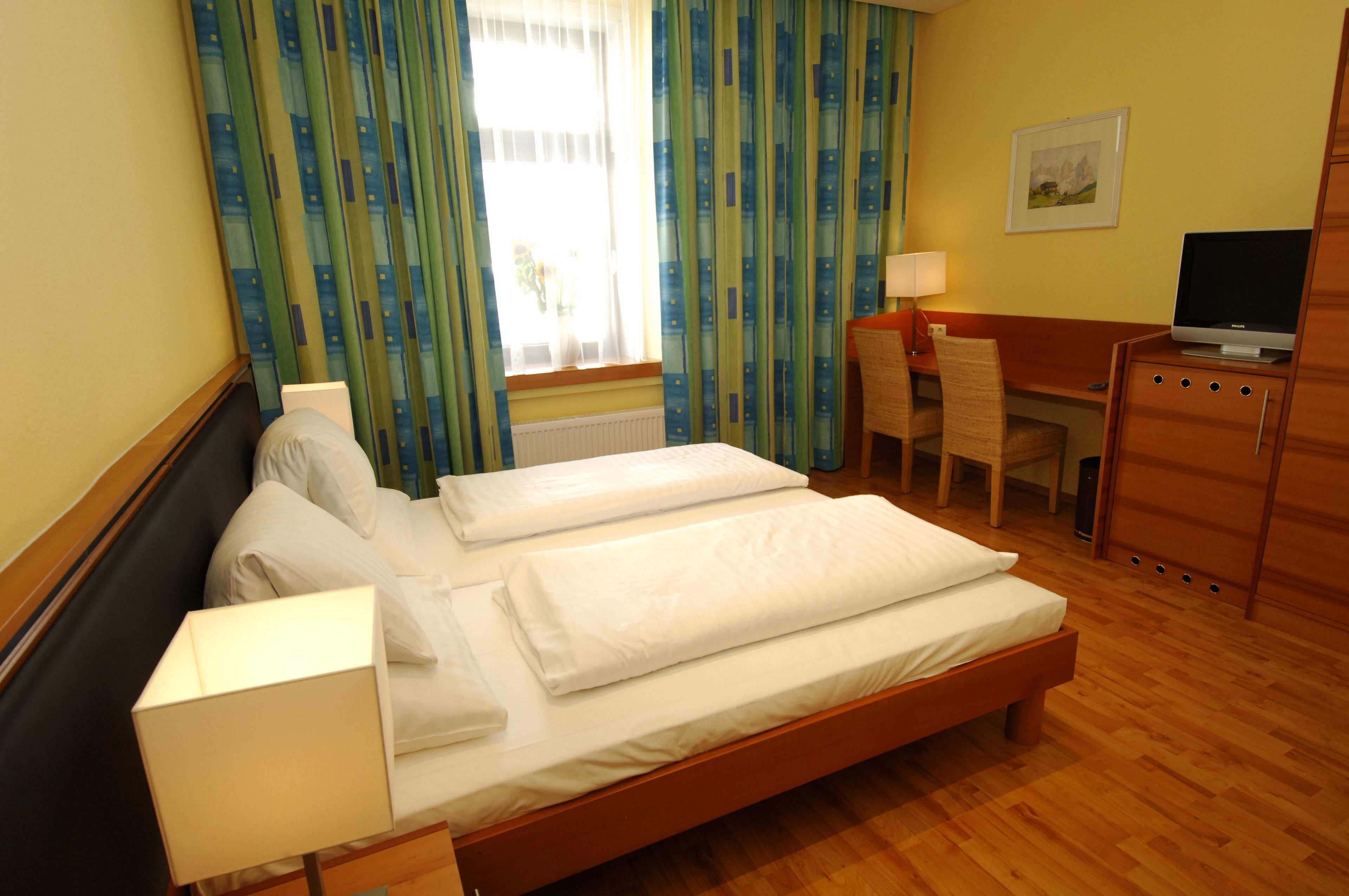 Una habitación de hotel con cama, escritorio, silla y televisor.