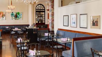 Un restaurante espacioso con candelabro, pisos de madera y asientos azules.