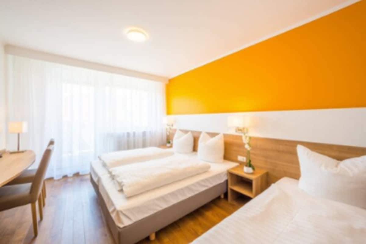 A hotel room with two beds, a wooden headboard, a desk, and a chair.