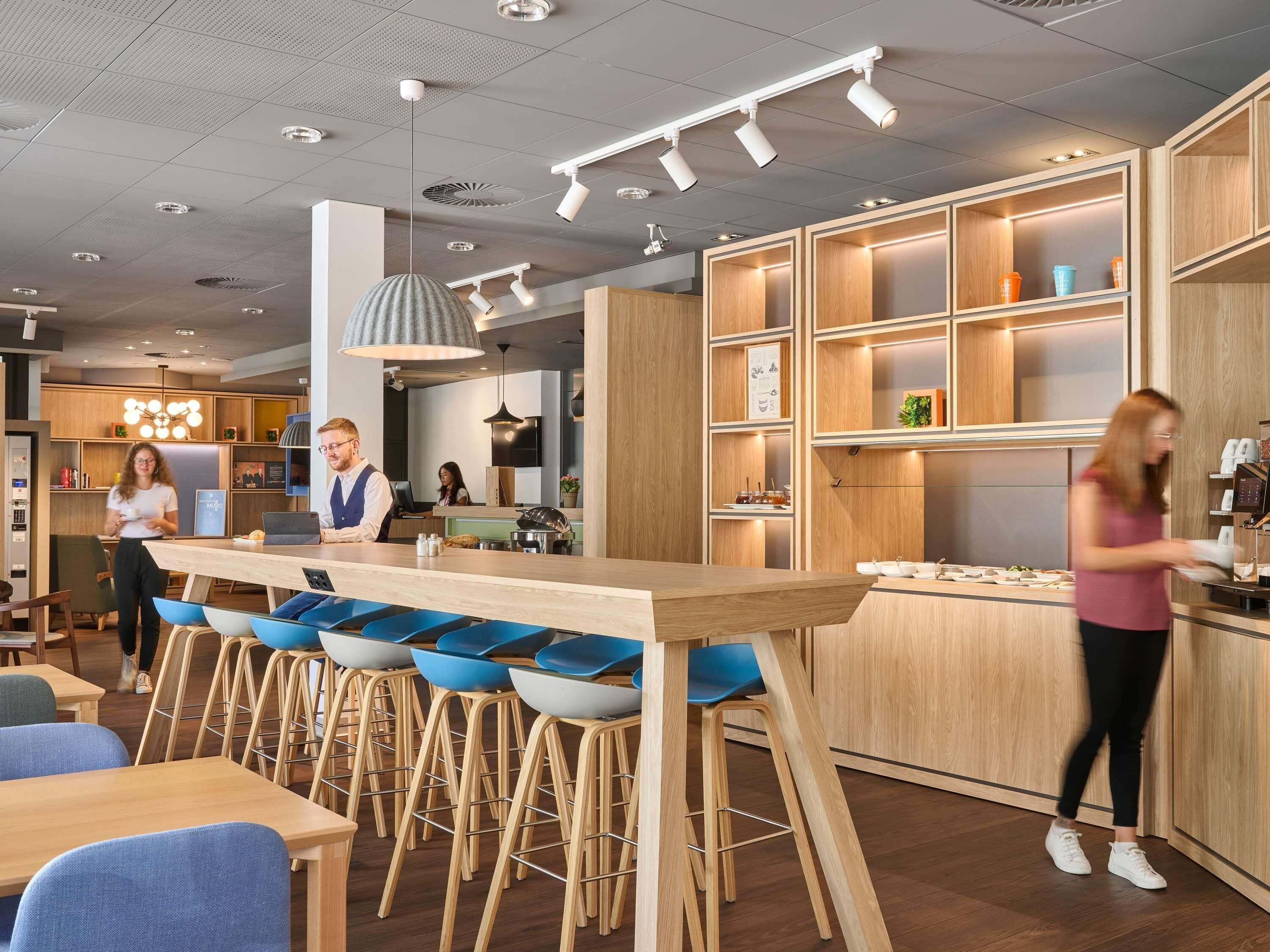 Un área de bar moderna con taburetes de madera, una barra y luces colgantes.