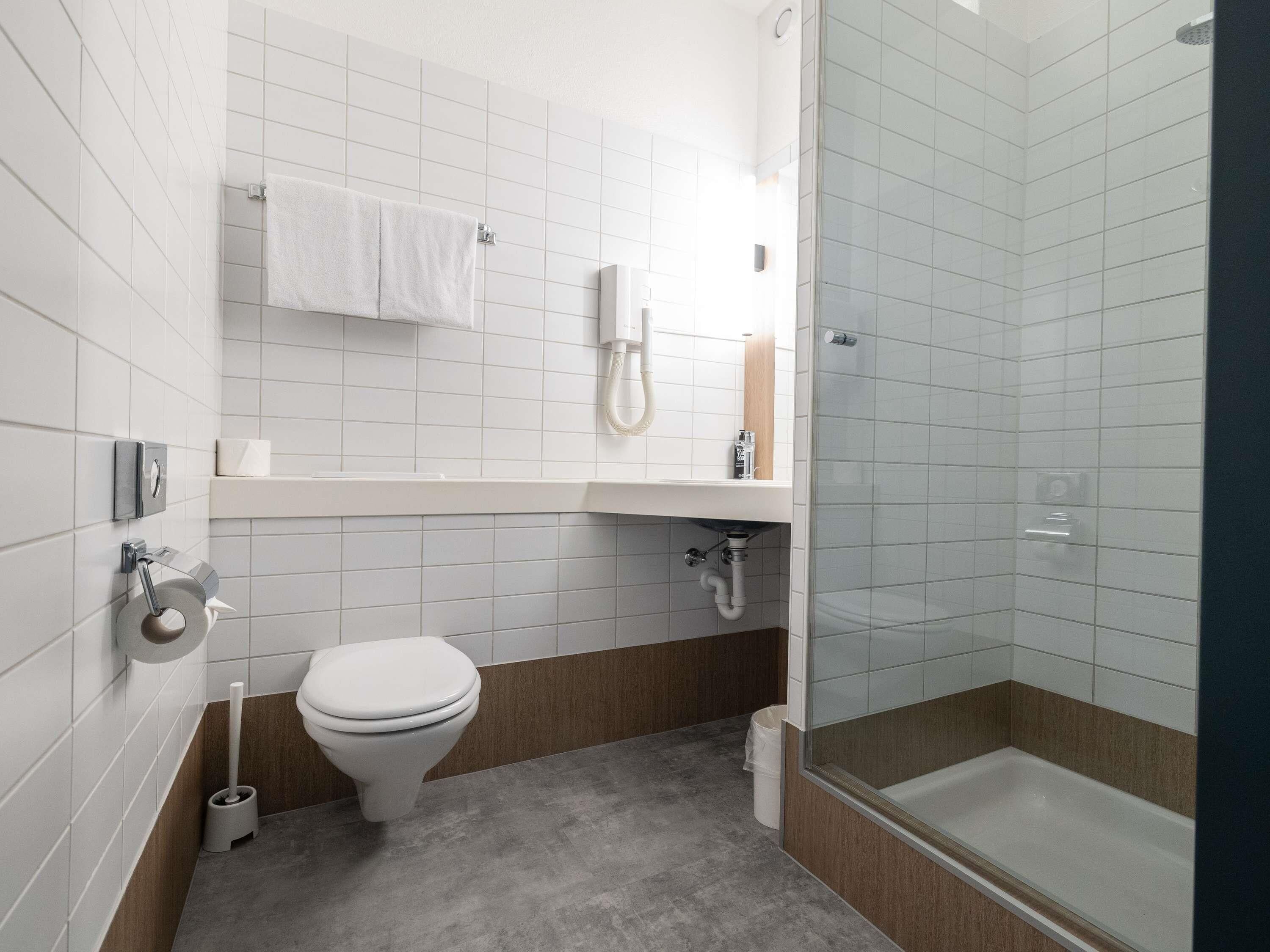 A modern bathroom with a toilet, sink, and shower.