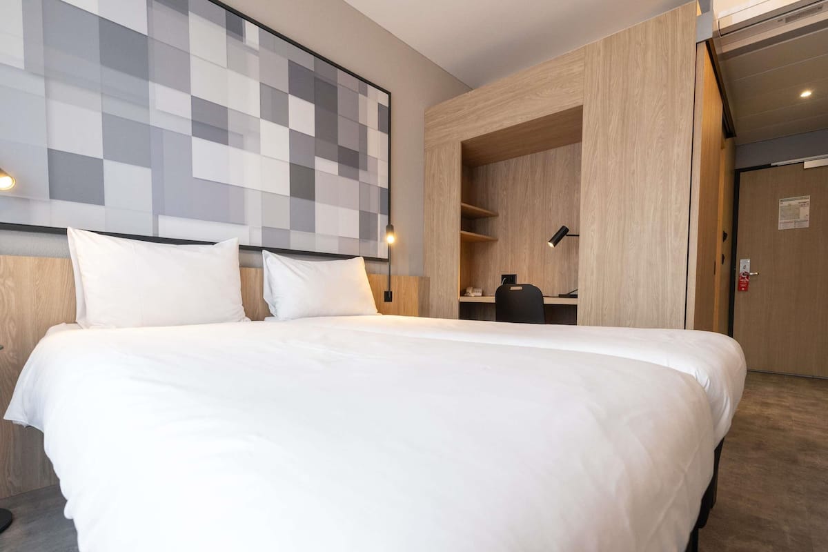 A hotel room with a large bed, a desk, and a wardrobe.