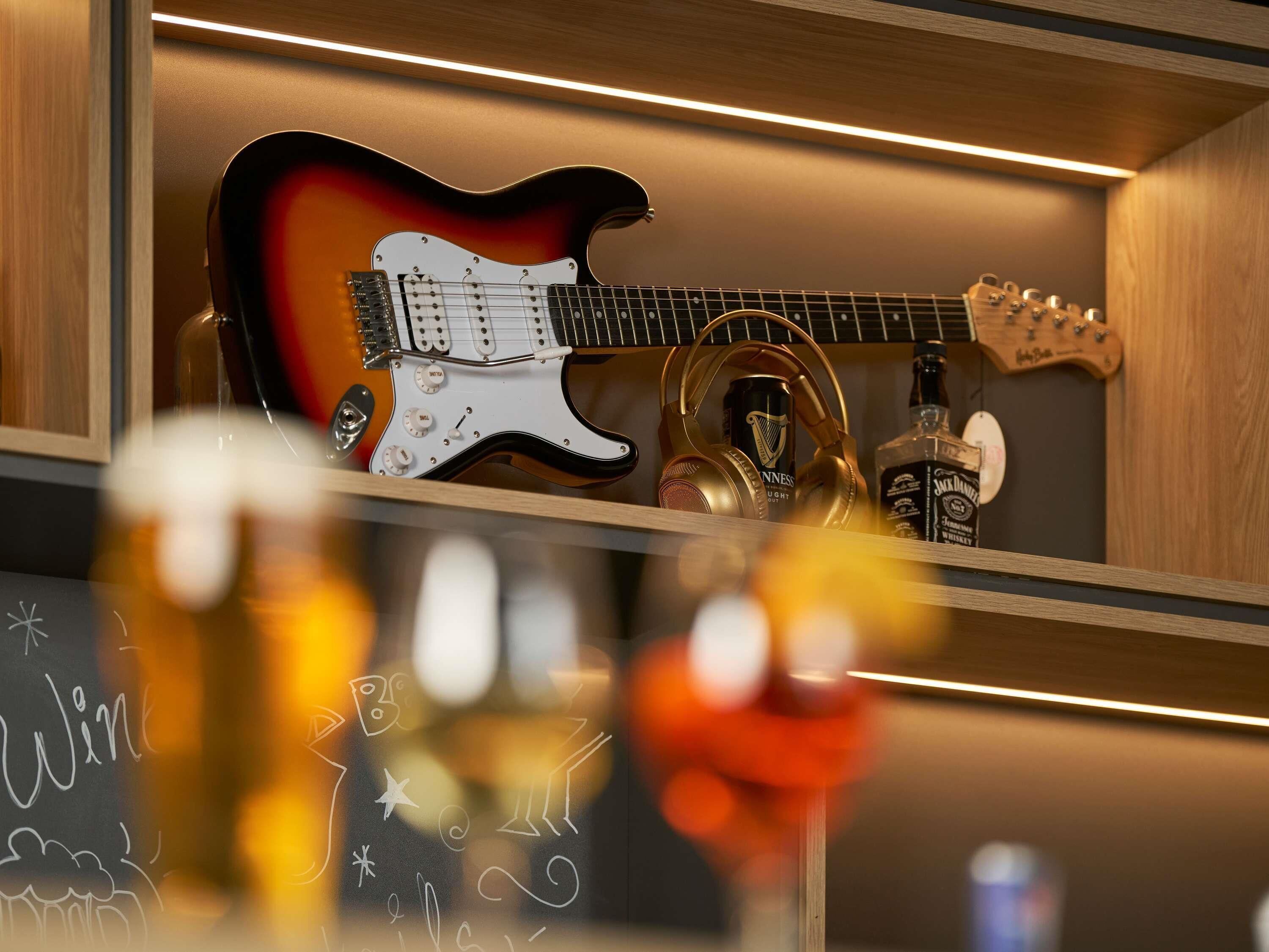 Una guitarra y auriculares sobre una estantería.