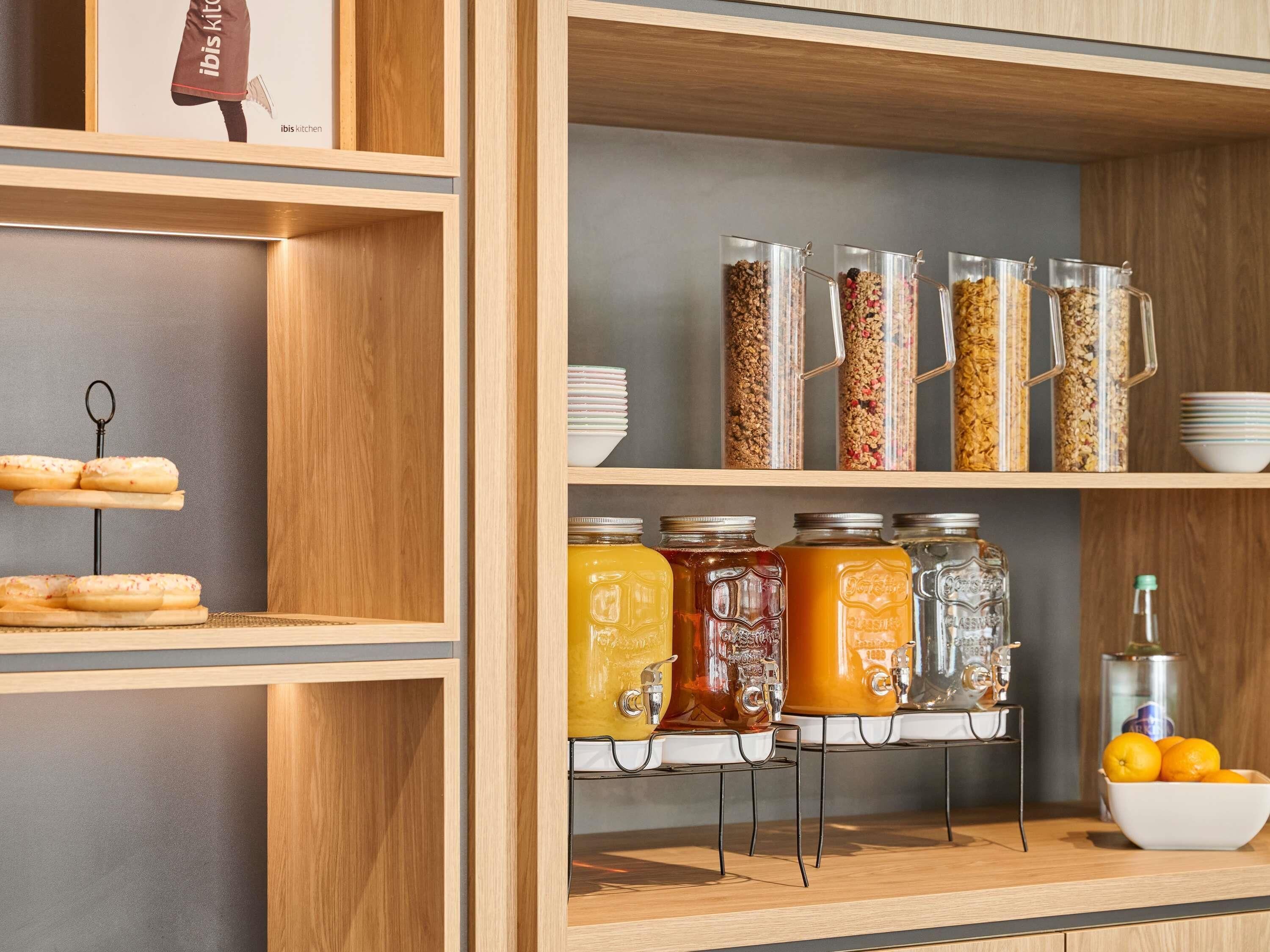 Una cocina con estantes de madera, frascos con alimentos y un cuenco de fruta.