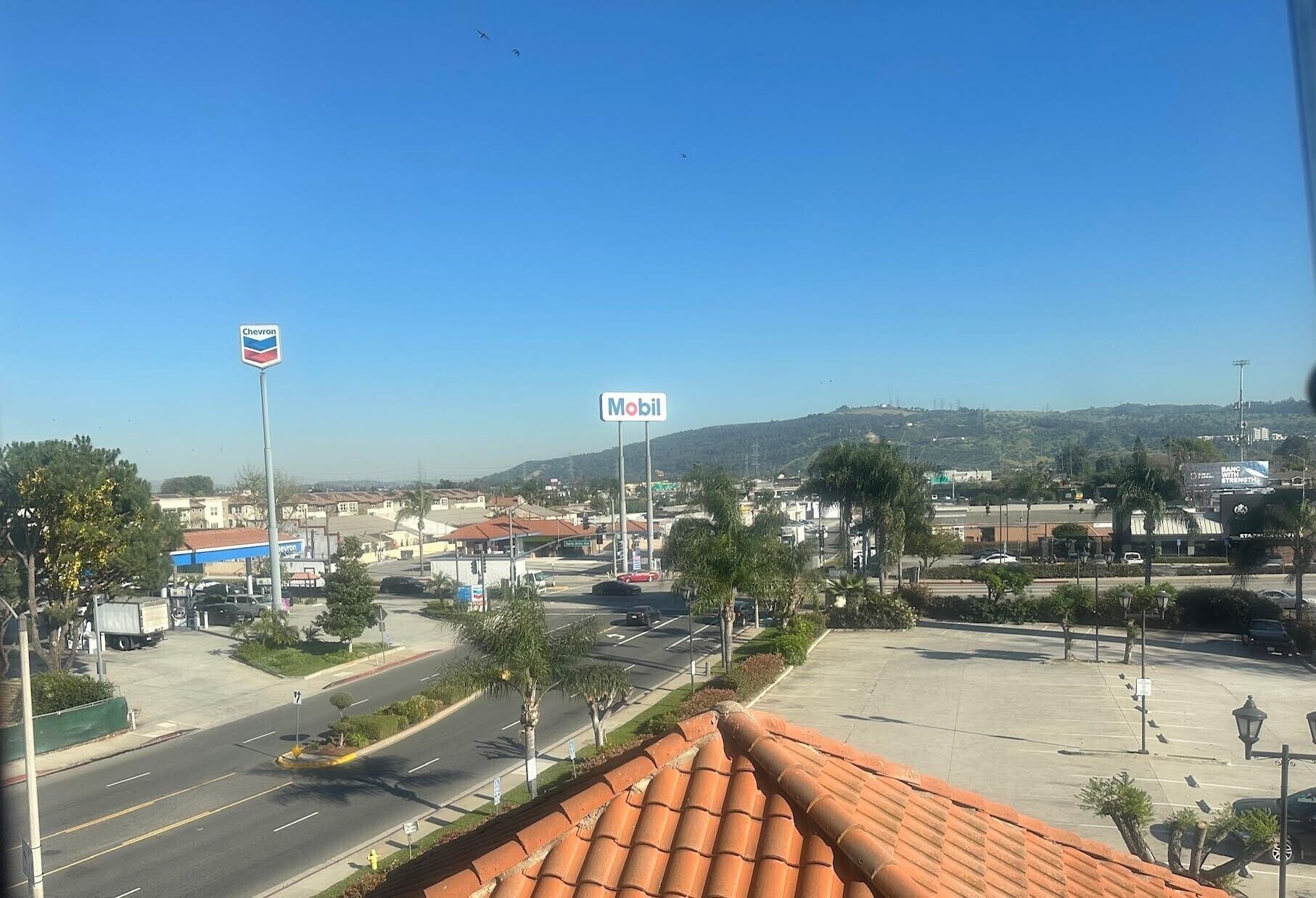 Un paisaje urbano con cielo despejado, una gasolinera Chevron y una gasolinera Mobil.
