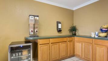 A kitchen with wooden cabinets, a coffee machine, a refrigerator, and a plant.