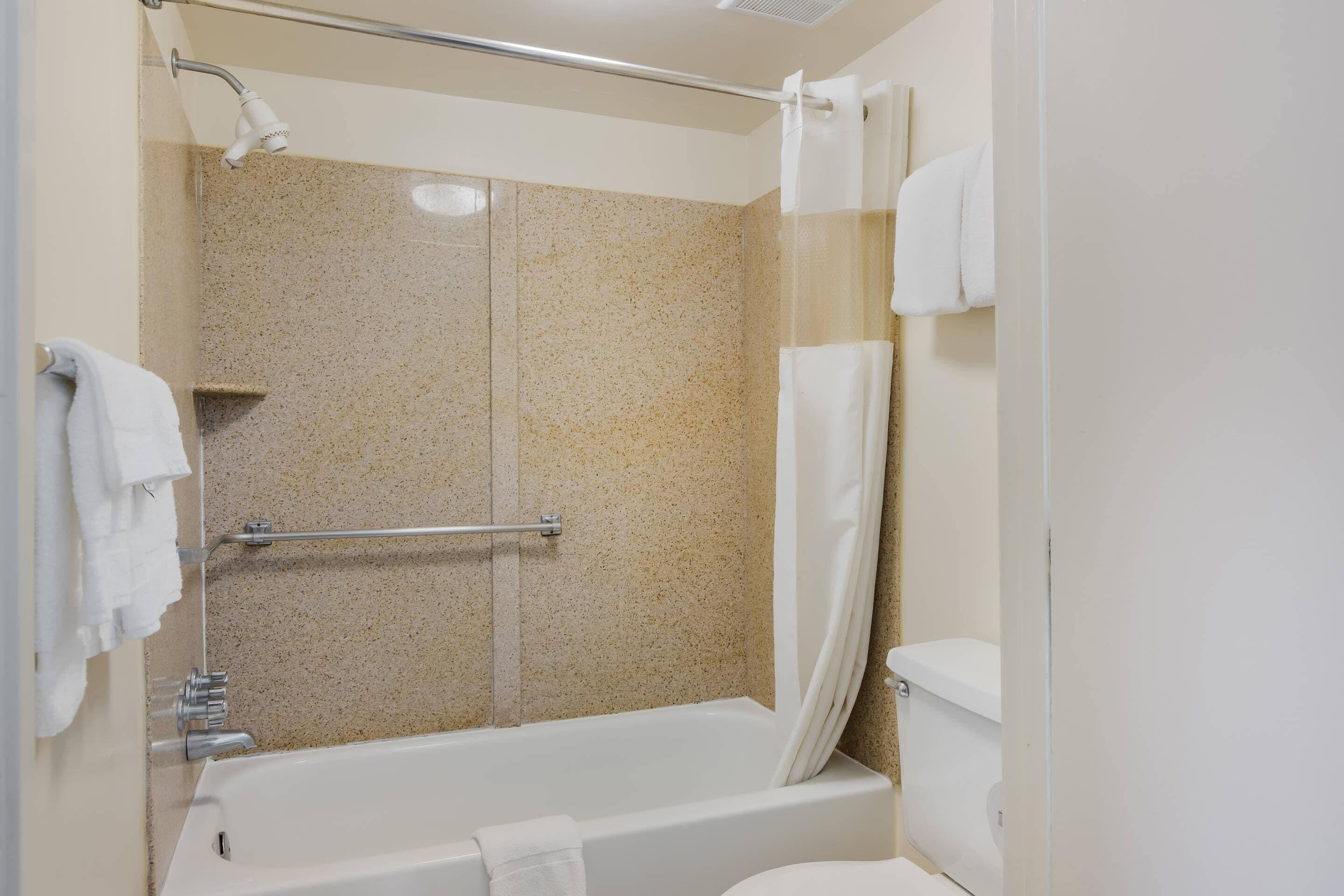 A bathroom with a bathtub, shower, and toilet.