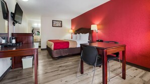 Habitació d'hotel amb llit, escriptori, cadira i televisió penjada a la paret.