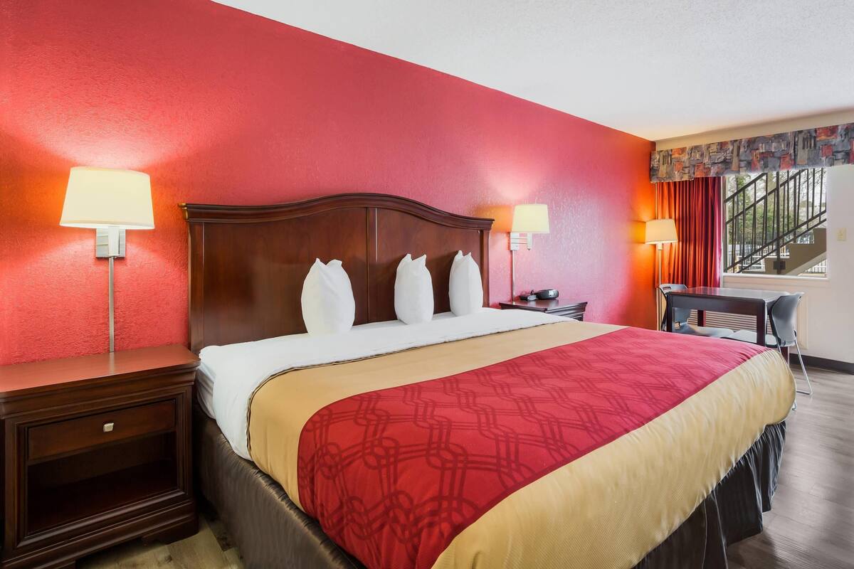 A hotel room with a large bed, two bedside tables, a desk, and a chair.