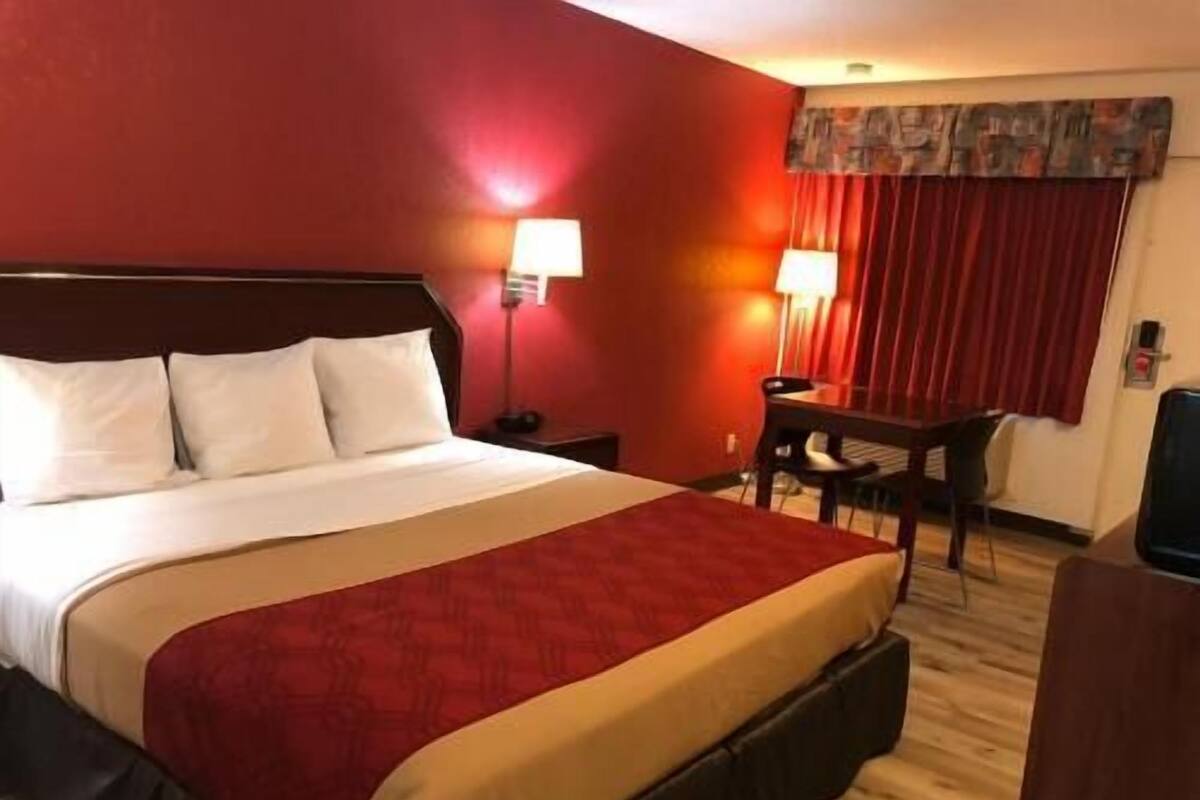 A hotel room with a bed, two bedside lamps, a desk, and a chair.
