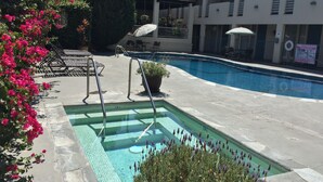 A swimming pool with a clear blue waterline, surrounded by lounge chairs and potted plants. - Mikado Hotel - Universal Studios/Burbank (Valley Village)