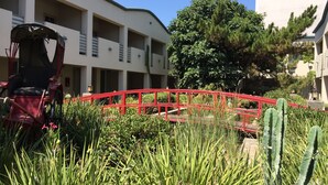 A courtyard with a red bridge, cacti, and a building with balconies. - Mikado Hotel - Universal Studios/Burbank (Valley Village)