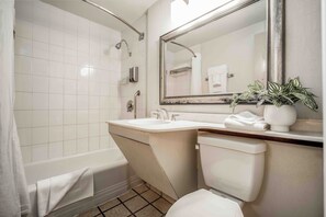 A bathroom with a bathtub, a sink, a toilet, and a mirror. - Mikado Hotel - Universal Studios/Burbank (Valley Village)