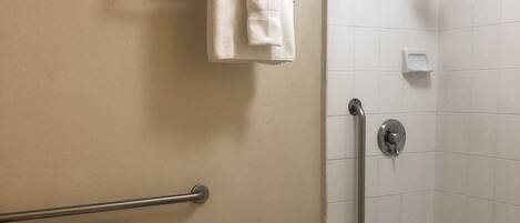 A bathroom with a toilet, a shower with a grab bar, and a bathtub.