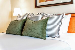 A bed with striped pillows and a green throw. - Mikado Hotel - Universal Studios/Burbank (Valley Village)