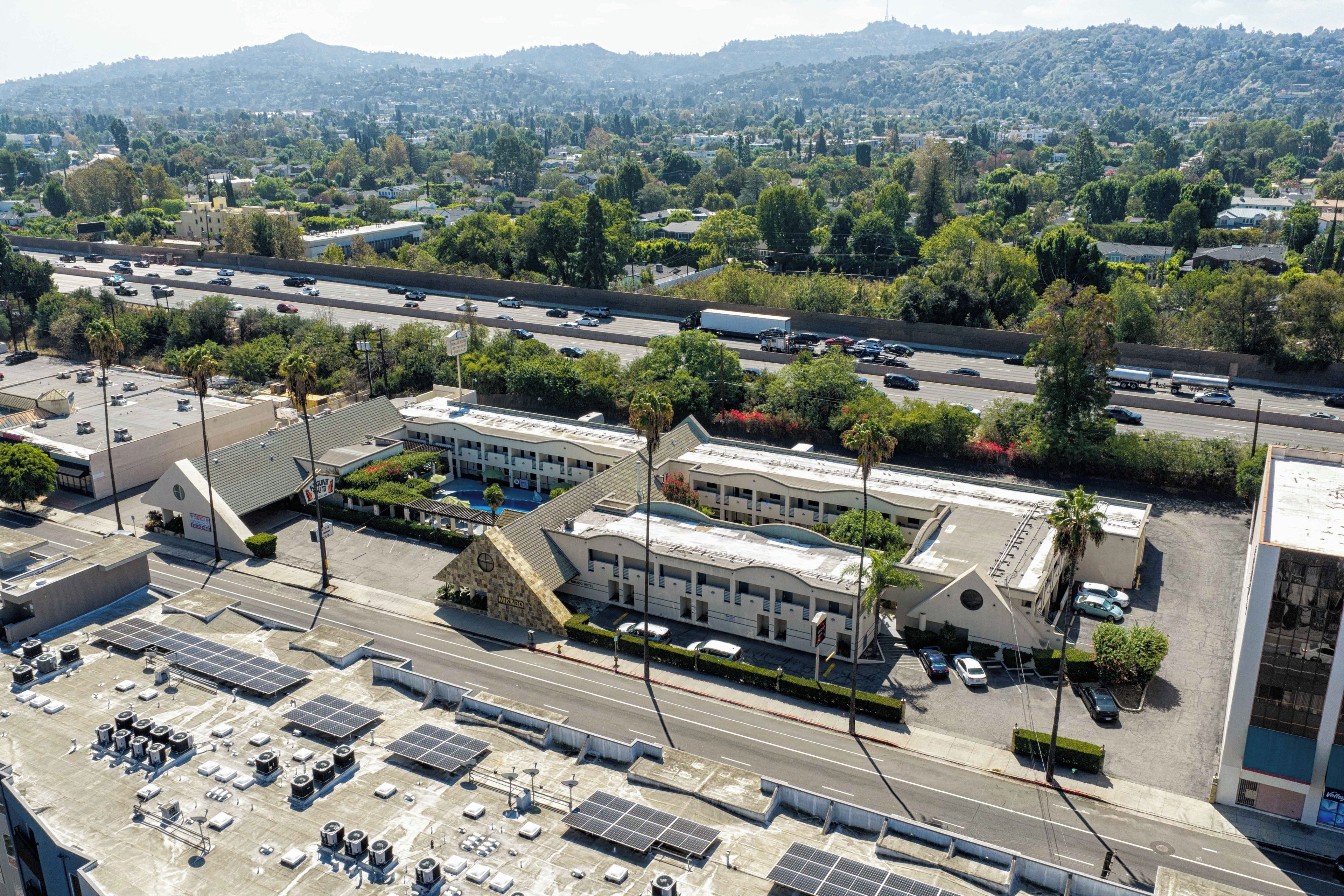 Un hotel de varios pisos con un estacionamiento en la azotea y paneles solares.