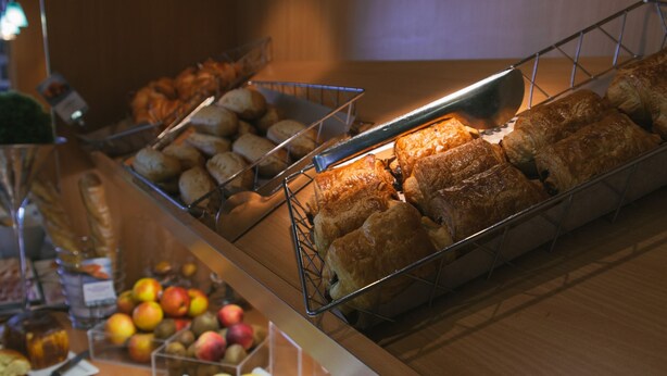 Un buffet proposant une variété de plats, notamment des pâtisseries, des fruits et des condiments.