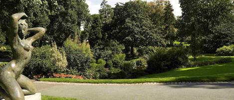 A sculpture in a park with a paved path and lush greenery.