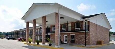A motel with a covered parking area, brick exterior, and multiple windows.